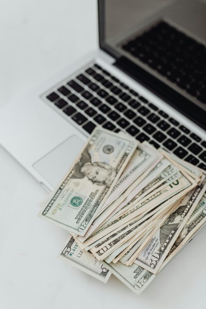 pexels-photo-5942602-5942602 Stack of US dollar bills on a laptop keyboard representing online finance and budgeting.
